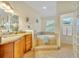 Bright bathroom with a soaking tub, granite vanity, and tiled floor, offering a spa-like experience at 210 Torcaso Ct, Winter Springs, FL 32708