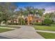 Beautiful home featuring a circular driveway lined with mature palm trees and lush landscaping at 210 Torcaso Ct, Winter Springs, FL 32708