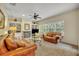 Cozy living room with a fireplace, built-in shelves, ceiling fan, and plush leather seating by bright windows at 210 Torcaso Ct, Winter Springs, FL 32708