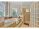 Luxurious main bathroom with a soaking tub, glass block shower, and natural light from the window at 210 Torcaso Ct, Winter Springs, FL 32708