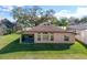 Back exterior of home with screen patio, large yard, and neutral color palette at 32107 Spring Meadow Ct., Sorrento, FL 32776