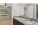 Bathroom with dual sinks, granite countertops, dark wood cabinets, and a view of the adjoining bedroom at 32107 Spring Meadow Ct., Sorrento, FL 32776