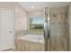 Bathroom showcasing a soaking tub and glass-enclosed shower with tiled walls and a window view at 32107 Spring Meadow Ct., Sorrento, FL 32776