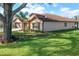 Exterior side view of home with well maintained lawn, mature tree, and manicured landscaping at 32107 Spring Meadow Ct., Sorrento, FL 32776