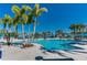 Large outdoor pool area with blue umbrellas and palm trees under a bright blue sky at 4058 Lana Avenue, Davenport, FL 33897