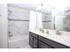 Beautiful bathroom with white marble style tiling in the shower/tub area and a double sink vanity with dark cabinetry at 4844 Romeo Cir, Kissimmee, FL 34746