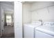 Neat laundry area with a white washer and dryer set, shelving, and doorway view into an adjacent bedroom at 4844 Romeo Cir, Kissimmee, FL 34746