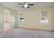 Spacious main bedroom featuring a ceiling fan, two windows, and ensuite bathroom access at 5023 Southlawn Ave, Orlando, FL 32811