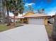 Charming home features a two-car garage, a well-manicured lawn, and beautiful landscaping with palm trees at 629 Nighthawk Cir, Winter Springs, FL 32708