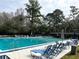 Community pool with blue lounge chairs, umbrellas, and mature trees at 629 Nighthawk Cir, Winter Springs, FL 32708