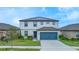 Two-story home with a blue garage door, well-manicured lawn, and solar panels on the roof at 630 Citrus Isle Blvd, Davenport, FL 33837