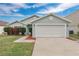 Charming single-story home with a two-car garage, manicured lawn, and landscaped front yard at 11223 Huxley Ave, Orlando, FL 32837