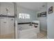 Bathroom featuring a soaking tub, a shower, a large window, and sleek black and white accents at 116 Douglas St, Edgewater, FL 32141
