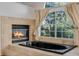 Bathroom featuring a black soaking tub, fireplace, and a large window at 1330 Shelter Rock Rd, Orlando, FL 32835