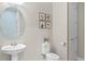Elegant powder room featuring a pedestal sink, round mirror, and stylish botanical wall art at 1380 Patterson Ter, Lake Mary, FL 32746