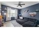 This spacious bedroom features modern blue walls, a ceiling fan, and plush seating area with an accent rug at 15373 Murcott Harvest Loop, Winter Garden, FL 34787