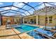 Beautiful screened-in pool and spa, surrounded by lounge chairs and lush landscaping, ideal for relaxing and entertaining guests at 1905 Estuary Ln, Kissimmee, FL 34747