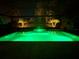 A luxurious pool and spa are lit up at night with palms and trees surrounding the backyard at 1905 Estuary Ln, Kissimmee, FL 34747