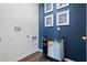 Laundry room with hardwood floor, white walls, blue accent wall and rolling laundry bin at 3178 Partington Blvd, Davenport, FL 33837