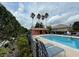 Community pool area with lounge chairs, palm trees, and a nearby building at 321 Davinci Pass, Kissimmee, FL 34759