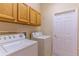 A laundry room with wooden cabinets, a white door, a washer, and a dryer at 321 Davinci Pass, Kissimmee, FL 34759