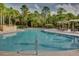 Large community pool area with lounge chairs, tables, and umbrellas, surrounded by palm trees and greenery at 3930 Hydrangea Ct, Oviedo, FL 32766