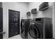 Modern laundry room featuring gray front load washer and dryer with baskets and black paneled door at 3930 Hydrangea Ct, Oviedo, FL 32766