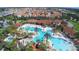 Aerial view of a community pool area with palm trees, waterslides, and lounge areas surrounded by homes at 5251 Wildwood Way, Davenport, FL 33837