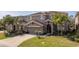 Beautiful two-story home features a well-manicured lawn, mature palms, a tile roof, and a two-car garage at 5251 Wildwood Way, Davenport, FL 33837