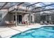 Covered patio with outdoor kitchen, grill, dining table, and lounge chairs overlooking the pool at 5251 Wildwood Way, Davenport, FL 33837