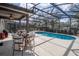 Beautiful screened-in pool area with cozy seating, dining area, and lush landscaping for privacy at 5251 Wildwood Way, Davenport, FL 33837