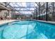 Screened-in pool with attached jacuzzi and sleek lounge chairs offers a private outdoor oasis at 5251 Wildwood Way, Davenport, FL 33837