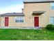 Charming two-story townhouse exterior featuring a well-maintained lawn and red entry doors at 601 Washington Palm Loop, Davenport, FL 33897