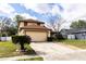 Tan two story home with a light garage door, landscaping, and a walkway leading to the front door at 7440 Windsome Ct, Orlando, FL 32810