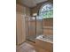 Bathroom featuring a large shower and garden tub with large arched window at 7741 Bardmoor Hill Cir, Orlando, FL 32835