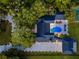 Aerial view of estate with a pool, patio seating, a long driveway illuminated with lights, and mature trees all around at 900 W Plant St, Winter Garden, FL 34787