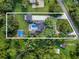 Aerial view of a luxury estate featuring a pool, sport court, and lush landscaping surrounded by trees and outlined property lines at 900 W Plant St, Winter Garden, FL 34787
