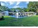 Sprawling backyard featuring a home exterior, pool, and lush green lawn with lounge areas and mature trees at 900 W Plant St, Winter Garden, FL 34787