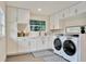 Bright laundry room with white cabinets, counter space, sink, and modern washer and dryer at 900 W Plant St, Winter Garden, FL 34787
