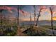 Scenic lake view with an old wooden dock, bare trees, and a colorful sunset reflecting off the calm water at 10433 Trout Rd, Orlando, FL 32836