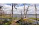Scenic lake view with an old wooden dock, bare trees, and clouds reflecting off the calm water at 10433 Trout Rd, Orlando, FL 32836