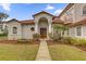Inviting home entrance featuring a tile roof, landscaped yard, and double doors framed by elegant columns at 10616 Emerald Chase Dr, Orlando, FL 32836