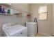 Functional laundry room featuring a washer, dryer, shelving, and a window for natural light at 1077 Fountain Coin Loop, Orlando, FL 32828