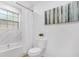 Bright bathroom features white marble tile, tub with shower, and white toilet at 1300 Montego Ln, Orlando, FL 32807