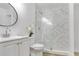 Bright bathroom features white vanity, glass shower with marble backsplash, and toilet with decorative orchid at 1300 Montego Ln, Orlando, FL 32807