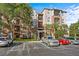 Three-story condo building with multiple balconies, lush trees, and parking, all under a bright blue sky at 1357 Venezia Ct # 402, Davenport, FL 33896