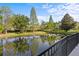 Backyard pond featuring lush trees and vegetation from behind a black fence at 1357 Venezia Ct # 402, Davenport, FL 33896
