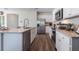This open kitchen features white cabinets, stainless appliances, a central island and dark wood floors at 3017 Moulin Rd, Davenport, FL 33837