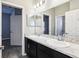 Bathroom with double sinks, a marble-look countertop, and a large mirror at 411 Lily Ln, Davenport, FL 33837