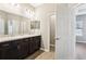Bathroom with dual sinks, dark cabinetry, and a large mirror at 411 Lily Ln, Davenport, FL 33837
